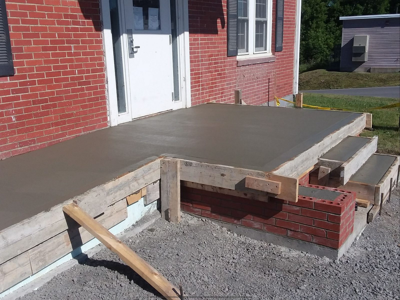 Freshly poured concrete patio at brick building